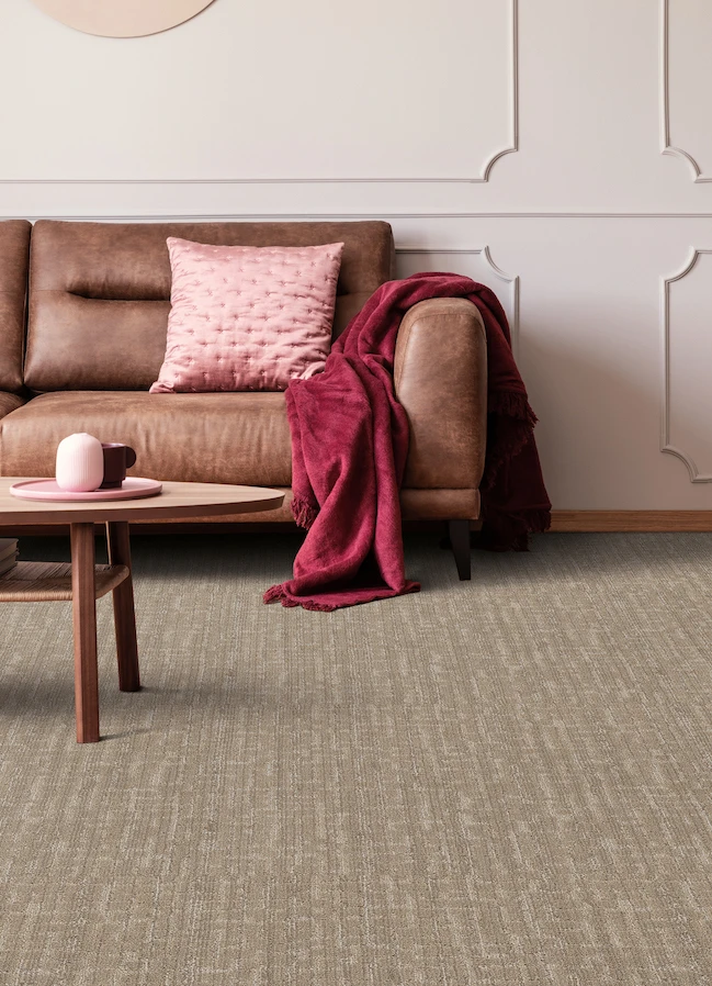 textured brown carpets in a modern living room with pale pink walls and brown leather couch